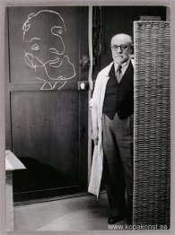 Henri Matisse står mot en skärm och ritar med krita